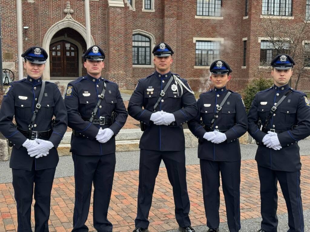 Five Auburn Police officers in dress uniform standing together outside a brick building